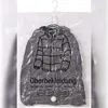 Transparenter Vakuum-Aufbewahrungsbeutel mit grauer Daunenjacke darin, hängend an einem weißen Plastikhaken Náhled obrázku produktu
