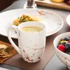 A table setting with a mug of tea, a plate of food, and a bowl of berries. Náhled obrázku produktu