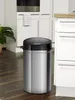 A stainless steel trash can with a black lid and sensor is shown in a kitchen setting. Produktbild-Vorschau