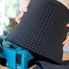 A person is holding a piece of black foam with a grid pattern over a blue toolbox. Produktbild-Vorschau
