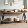 A long, narrow console table with a rustic wood top and black metal legs, placed behind a sofa in a living room. It is decorated with a vase of flowers, books, picture frames, and a lamp. Anteprima dell’immagine prodotto
