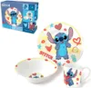 A Disney Stitch themed porcelain dinnerware set, including a plate, bowl, and mug, displayed with its packaging. Voir les images du produit