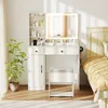 A white vanity set with a lighted mirror, stool, and storage is shown in a bedroom setting next to a bed. Voir les images du produit