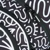 A close-up view of a black backpack with a white abstract pattern and zippers. Podgląd zdjęcia produktu