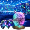 A child's bedroom decorated with glow-in-the-dark dinosaur stickers and stars, illuminated by a colorful egg-shaped lamp and two smaller star projectors. Voir les images du produit