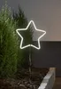 A white neon star light is placed in a garden bed next to a green bush. Podgląd zdjęcia produktu