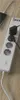 A close-up view of a white power strip with multiple outlets and USB ports, plugged into a wooden surface. Produktbild-Vorschau