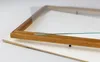 A close-up view of a wooden picture frame with a piece of glass resting on it, placed on a white backing board. Produktbild-Vorschau