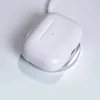 A white wireless charging case for earbuds is placed on a white surface. Produktbild-Vorschau