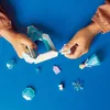 Children's hands assembling a LEGO Disney Frozen castle playset on a blue surface. Podgląd zdjęcia produktu