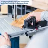 A person is using a band saw to cut a piece of wood. The band saw is a blue and gray machine with a wooden plank on its table. The person's hands are visible, guiding the wood into the saw blade. The image is cropped to focus on the action. Produktbild-Vorschau
