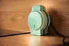 A mint green electrical device is placed on a wooden surface against a wooden background. Podgląd zdjęcia produktu