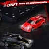 Two remote control drift cars, one red and one black with gold accents, are shown on a dark surface, possibly a desk, with a keyboard in the background. The cars have illuminated headlights. Náhled obrázku produktu
