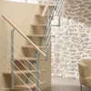 A modern indoor staircase with wooden steps and a metal railing against a stone wall and a beige wall. Produktbild-Vorschau