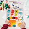 A child's hands interacting with a colorful educational toy on a table, with drawing supplies scattered around. Podgląd zdjęcia produktu