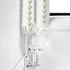 A close-up of a clear plastic bracket holding a beaded cord for a window blind. Produktbild-Vorschau