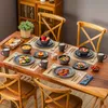 A dining table set for a meal with plates, bowls, cups, and food. Produktbild-Vorschau