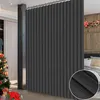 A dark gray room divider curtain is shown in a room with a Christmas tree and gifts on the left, and a bed with pillows on the right. Náhled obrázku produktu