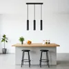 A modern kitchen island with pendant lights, stools, and decorative items. Náhled obrázku produktu