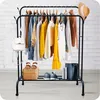 A clothing rack with various garments and accessories displayed against a white brick wall. Anteprima dell’immagine prodotto