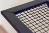 A close-up view of the corner of a black metal mesh grid within a black frame. Anteprima dell’immagine prodotto