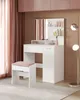 A white vanity set with a mirror and stool in a room with pink and brown accents. Produktbild-Vorschau