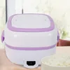 A white and purple electric lunch box is placed on a wooden surface in front of a blurred background. Náhled obrázku produktu