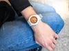 A person wearing a white and orange Casio G-Shock watch on their wrist, sitting down with blue jeans. Anteprima dell’immagine prodotto