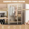 A white metal and wood garment rack with clothes hanging on it and shelves for storage, set in a room with a bed and curtains. Produktbild-Vorschau