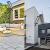 A split image showing a solar street lamp mounted on two different modern buildings, one with a patio and the other with an outdoor staircase. Produktbild-Vorschau