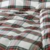 A close-up view of a white pillowcase with a red, green, and gray plaid pattern. Produktbild-Vorschau