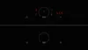 A close-up view of a black induction hob with red digital displays and controls. Voir les images du produit
