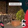 A wicker basket filled with firewood is placed in front of a large stack of firewood, with a bush in the background. There are marketing overlays on the image. Náhled obrázku produktu