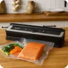 A vacuum sealer with food items on a wooden countertop. Podgląd zdjęcia produktu
