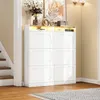 A white shoe cabinet with six flip-down doors and an open shelf with LED lighting, placed in a hallway next to a staircase. Náhľad obrázku produktu
