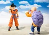 Two action figures, Son Goku and Master Roshi, posed on a sandy beach with a cloudy sky background. Produktbild-Vorschau