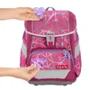 Hands are shown attaching decorative patches to a pink backpack. Produktbild-Vorschau