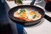 A frying pan with food being cooked in it, placed on a kitchen counter. Produktbild-Vorschau