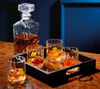 A crystal decanter and four glasses filled with amber liquid and ice, arranged on a wooden surface. Produktbild-Vorschau