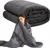 A woman is wrapped in a weighted blanket, with a folded weighted blanket in the background. Produktbild-Vorschau