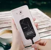 A person is holding a smartphone with a wireless charging adapter attached to the back, with a cup of coffee in the foreground. Náhľad obrázku produktu