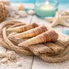 Seashells arranged on a rope and driftwood with a candle and starfish in the background. Produktbild-Vorschau