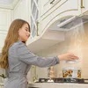 A woman is cooking in a modern kitchen with a range hood. Náhled obrázku produktu