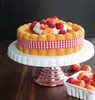 A cake decorated with fruit and cream on a cake stand. Produktbild-Vorschau