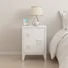 A white nightstand with a lamp, a framed picture, and a cup of coffee on top, placed next to a bed. Voir les images du produit