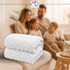 A family is sitting on a couch, with two folded white blankets in the foreground. Náhled obrázku produktu
