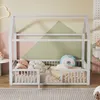 A child's house bed with bedding and pillows in a room with a colorful geometric wall. Anteprima dell’immagine prodotto