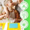 A child and an adult are in a kitchen, preparing food. The child is smiling and holding a whisk, while the adult has their arm around the child. There are also some kitchen tools and a yellow mat in the foreground. Produktbild-Vorschau