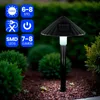 A solar-powered garden light with a conical lampshade is shown in a garden setting at dusk. Anteprima dell’immagine prodotto
