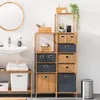A bathroom with a sink, mirror, and bamboo shelving unit filled with storage baskets and accessories. Anteprima dell’immagine prodotto